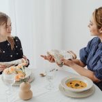 A mother and daughter share a meal, focusing on table etiquette and bonding over lunch.